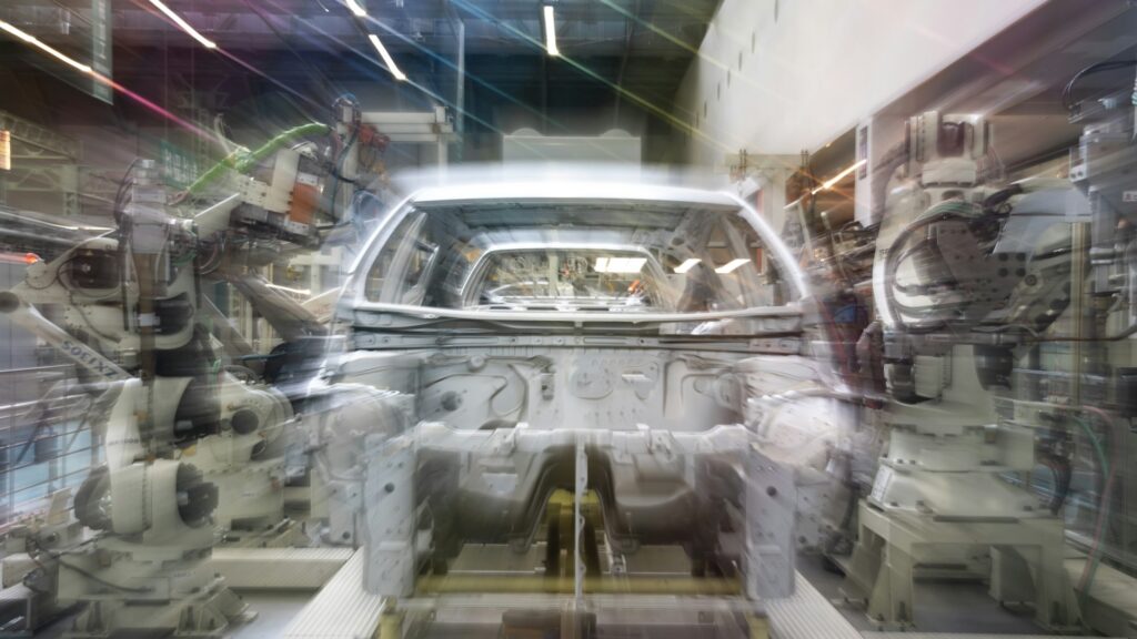 Línea de ensamblaje de autos con brazos robóticos en una planta de manufactura